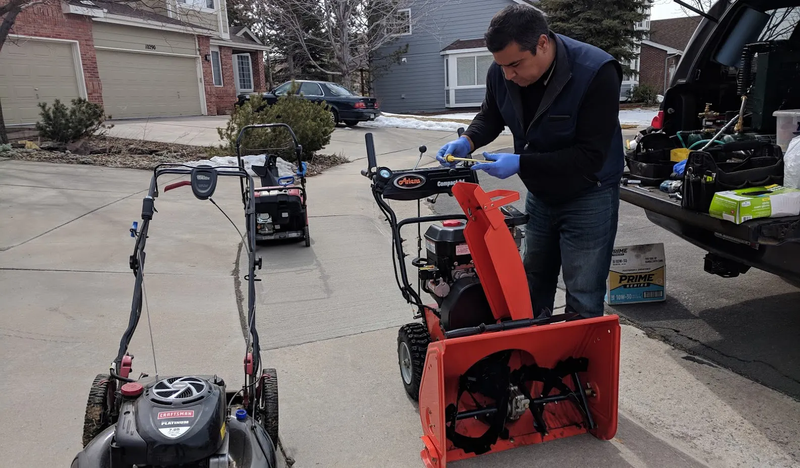 Mobile repair tech servicing a snowblower in a Denver driveway